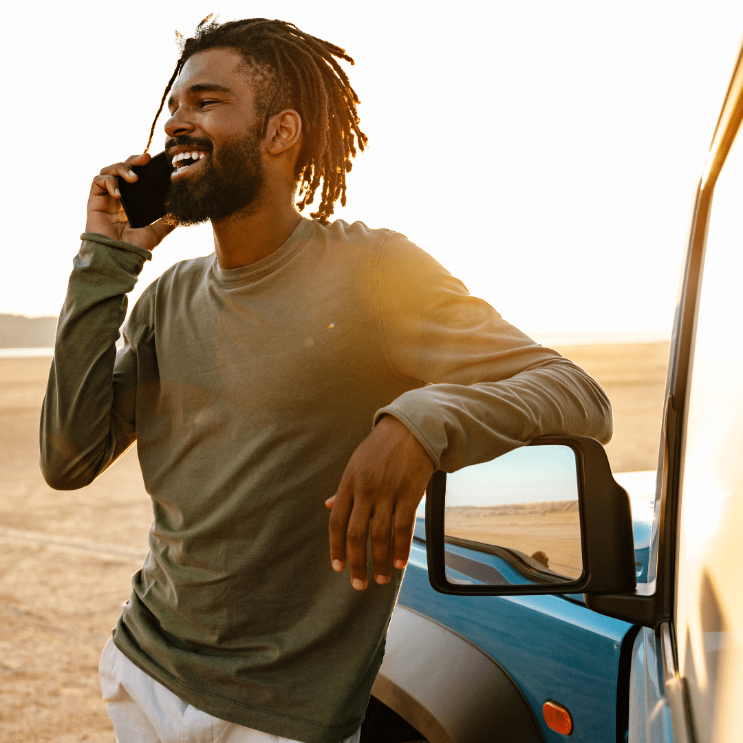 man with vehicle on beach making cell phone call
